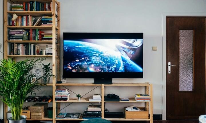 black flat screen tv turned on near brown wooden shelf