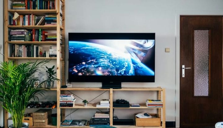 black flat screen tv turned on near brown wooden shelf