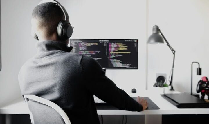 man in black long sleeve shirt wearing black headphones sitting on chair