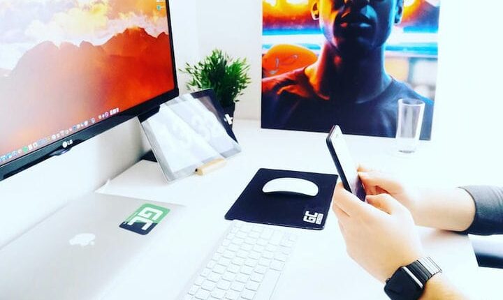 person holding smartphone near monitor