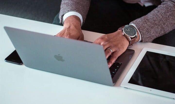 man using MacBook between iPad and iPhone